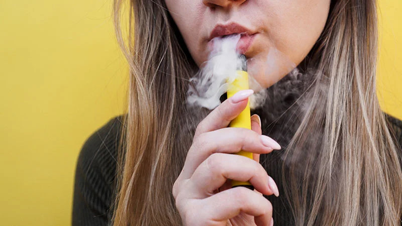 En random tjej med en vape i handen och rök från munnen